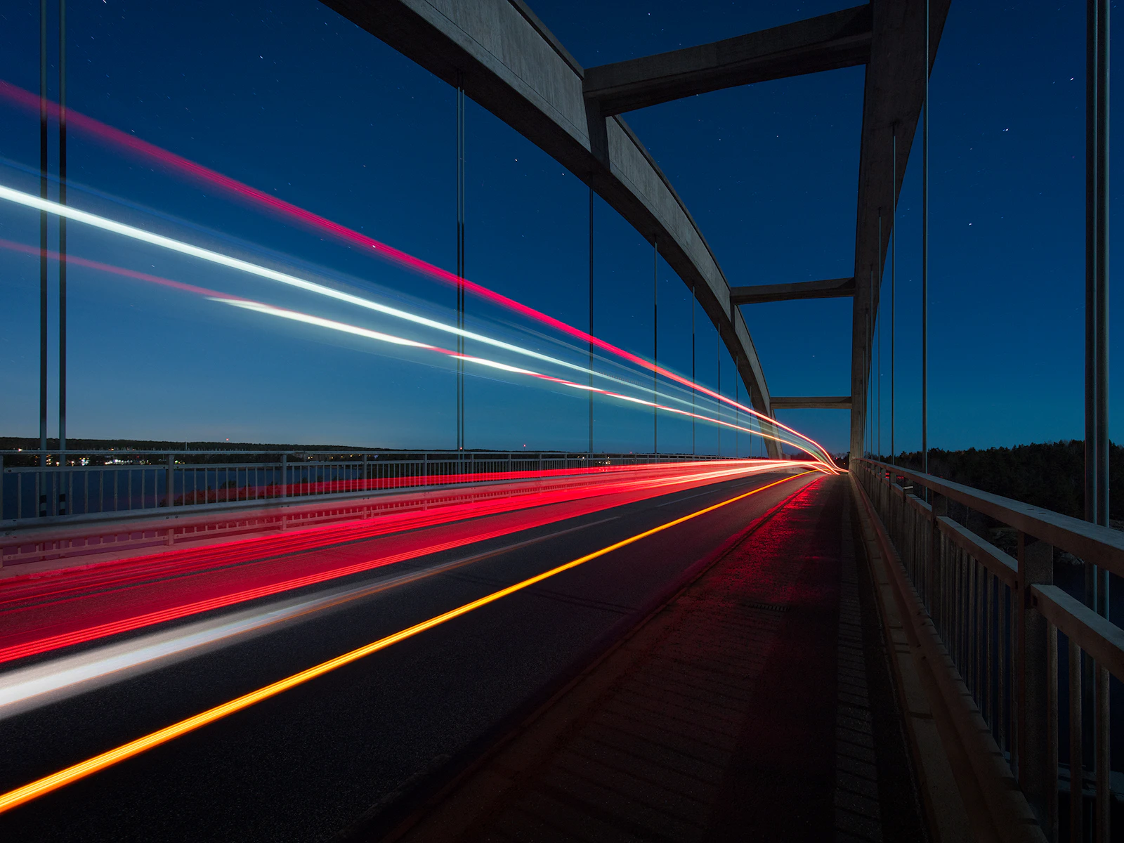 Light trails streaking across a bridge at night
